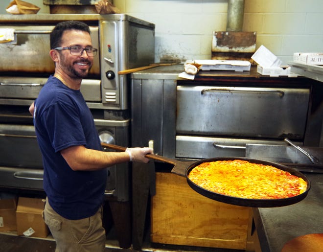 Vaggos Ntagkinis of the Supreme House of Pizza takes out a freshly made cheese pizza to get it ready for a customer on Tuesday, Nov. 14, 2023.