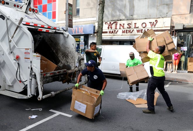 Three sanitation workers gather cardboard boxes in Mount Vernon, New York on Jan. 3, 2024.